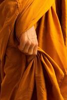 primo piano delle mani del monaco che tengono le sue vesti. foto