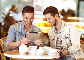 due giovani uomini / studenti che utilizzano computer tablet nella caffetteria