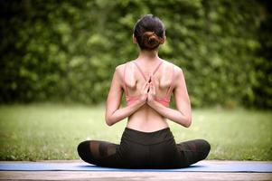 la meditazione e lo stretching delle donne asiatiche rilassano i muscoli facendo yoga in giardino foto