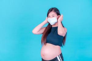 le donne asiatiche in gravidanza devono usare maschere per proteggersi dall'inquinamento da polvere e per prevenire l'infezione da virus foto