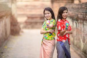 belle donne asiatiche tengono pistole ad acqua di plastica in un antico tempio durante il Songkran, il festival dell'acqua più bello e divertente della Thailandia foto