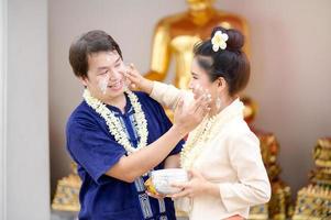 uomini e donne thailandesi in costumi thailandesi usano polvere solubile in acqua per dipingere le loro guance con gioia nel celebrare il festival dell'acqua di Songkran foto