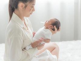 una bella donna asiatica mette il suo neonato sul suo corpo foto