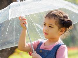 una bambina era felicemente in piedi sotto un ombrello contro la pioggia foto