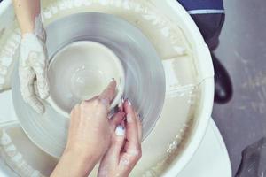 donna che fa ceramica sulla ruota, primo piano delle mani. concetto per donna in freelance foto