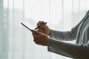 donna che tiene tablet e scrive su di esso, persona con dispositivo vista laterale primo piano foto