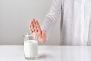 donna con intolleranza al lattosio che rifiuta un bicchiere di latte foto