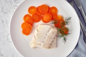 merluzzo bollito con carota e aneto su piatto bianco, dieta paleo fodmap dash foto