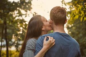 ragazza che bacia ragazzo in guancia nel parco, concetto di amore per adolescenti foto