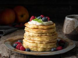 pancake con crema alla vaniglia, mirtilli e lamponi. vista laterale foto