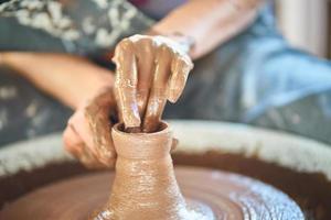 donna che fa ceramiche su ruota, primo piano delle mani, creazione di articoli in ceramica foto