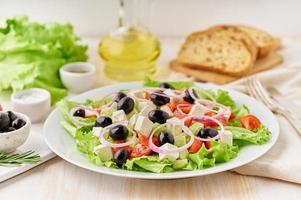 insalata greca su piatto bianco sul vecchio tavolo in legno bianco rustico, insalata fresca foto