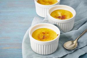 crema catalana, dessert spagnolo in tre ramekin su tavola blu, copia spazio foto