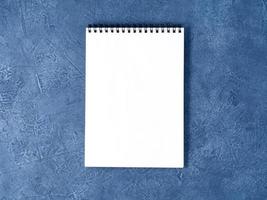 il blocco note aperto con una pagina bianca pulita su un tavolo in pietra blu scuro invecchiato, vista dall'alto foto