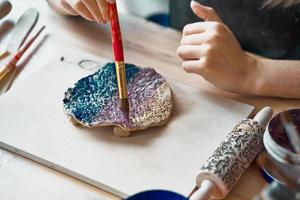 donna non riconosciuta che fa il modello su piatto di ceramica, primo piano delle mani, fuoco sui palmi con il pennello. concetto di hobby creativo. guadagnare soldi extra, fare affari, trasformare gli hobby in denaro, la passione in lavoro foto