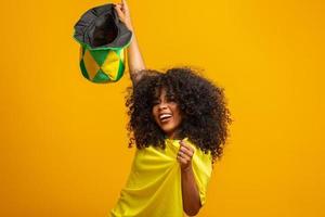 sostenitore del Brasile. fan della donna brasiliana che celebra una partita di calcio o di calcio su sfondo giallo. colori brasiliani. foto