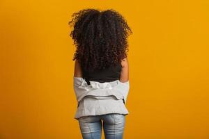 giovane donna nera sulla schiena con acconciatura afro su sfondo giallo. ragazza con acconciatura africana. girato in studio. foto