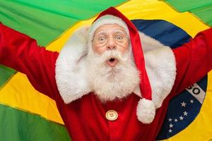 Babbo Natale è un fan del Brasile. tifoso di babbo natale della squadra brasiliana. campionato sportivo. Babbo Natale che tiene la bandiera brasiliana. partita di calcio. foto