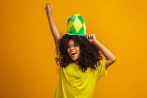 sostenitore del Brasile. fan della donna brasiliana che celebra una partita di calcio o di calcio su sfondo giallo. colori brasiliani. foto