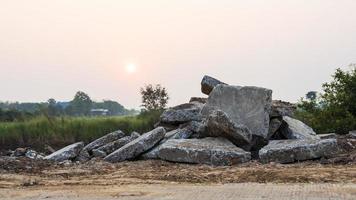 una vista ravvicinata di grandi macerie di cemento ammucchiate a terra da una demolizione di una strada di campagna. foto