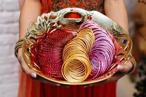 donna che tiene un piatto di braccialetti indiani colorati foto