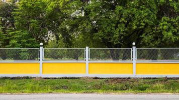 recinzione in muro di cemento giallo con giardino forestale. foto