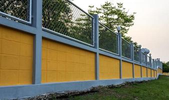 recinzione di muro di cemento giallo con grata in acciaio nel giardino forestale. foto