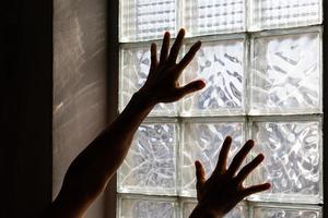 mani vicino al muro di mattoni di vetro. foto