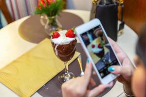 donna che scatta foto di un delizioso gelato bianco si fonde fragola con uno smartphone.