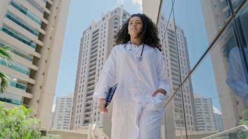 la giovane dottoressa latina indossa l'uniforme bianca, utilizzando la tavoletta digitale in ospedale foto