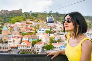 giovane turista caucasica guarda attraverso la finestra alla città vecchia in funivia, tbilisi, georgia foto