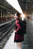 donna giovane viaggiatore in cerca di un viaggio di pianificazione amico alla stazione ferroviaria. concetto di stile di vita estivo e di viaggio foto