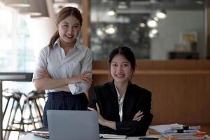 due belle donne d'affari asiatiche attraenti si siedono e parlano e guardano la telecamera. foto