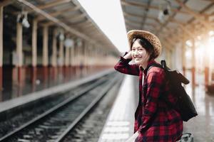 donna giovane viaggiatore in cerca di un viaggio di pianificazione amico alla stazione ferroviaria. concetto di stile di vita estivo e di viaggio foto
