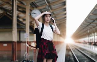 donna giovane viaggiatore in cerca di un viaggio di pianificazione amico alla stazione ferroviaria. concetto di stile di vita estivo e di viaggio foto