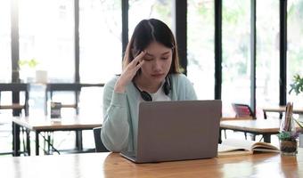 studente asiatico serio e concentrato che usa il laptop in cucina, guarda lo schermo con attenzione e concentrazione, guarda webinar di apprendimento, formazione virtuale, corso video, studia da casa foto