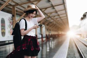 donna giovane viaggiatore in cerca di un viaggio di pianificazione amico alla stazione ferroviaria. concetto di stile di vita estivo e di viaggio foto