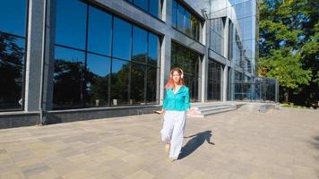 giovane donna con abito colorato e capelli rosa beve caffè e ascolta musica nel parco foto