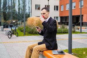 l'uomo d'affari lavora all'aperto con laptop e cellulare foto