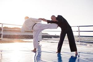 combattenti di karate stanno combattendo sul ring di pugilato della spiaggia al mattino foto