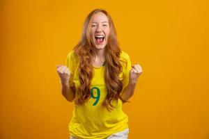 sostenitore del Brasile. fan della donna rossa brasiliana che celebra il calcio, partita di calcio su sfondo giallo. colori brasiliani. foto