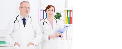 medici maschi e femmine che posano in studio medico, loro con stetoscopi, copia spazio, banner o cartellone foto