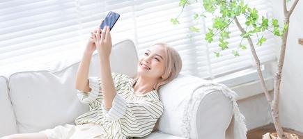 giovane ragazza asiatica che utilizza smartphone a casa foto