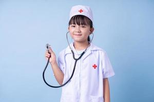 immagine del bambino asiatico che indossa l'uniforme del medico su sfondo blu foto