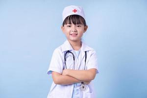 immagine del bambino asiatico che indossa l'uniforme del medico su sfondo blu foto