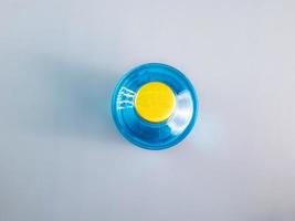 bottiglia di soluzioni di alcol etilico 70 per cento prelevate dall'alto. è un berretto giallo dorato. un liquido azzurro con riflessi su fondo grigio. foto