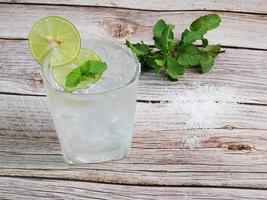 bevanda fredda al limone soda succo di limone con soda su ghiaccio guarnito con limoni a fette per guarnire. applicare il succo di limone e il sale sulla bocca del bicchiere. guarnire con foglioline di menta sopra. come bevanda foto