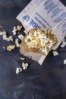 popcorn del sacchetto aperto strappato e che si rovescia su una superficie piatta foto