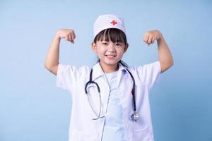 immagine del bambino asiatico che indossa l'uniforme del medico su sfondo blu foto