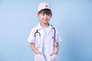 immagine del bambino asiatico che indossa l'uniforme del medico su sfondo blu foto